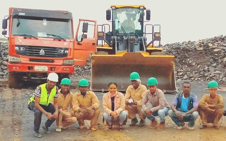Senselet Construction certified field engineers and machinery operators in front of heavy Sinotruk HOWO tipper and wheel loader equipment.